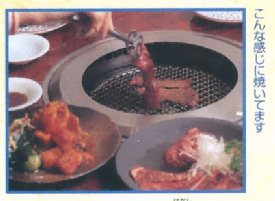 meat being placed on a korean bbq grill with other plates of food in the foreground.