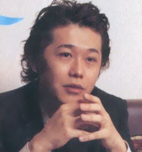 photo of taniguchi. he has very curly, slicked back hair.